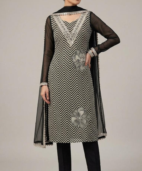 The shirt (kameez) is adorned with a continuous black and cream chevron (zigzag) print, creating a dynamic visual texture that elongates the frame.